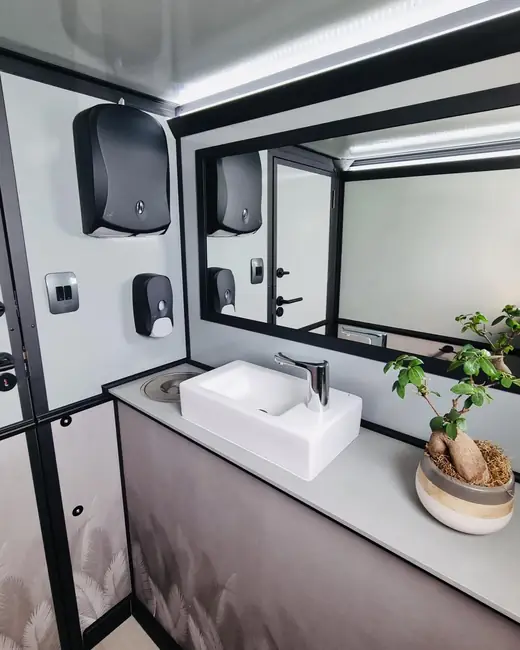 Restroom trailer sink with a large mirror and soap dispenser