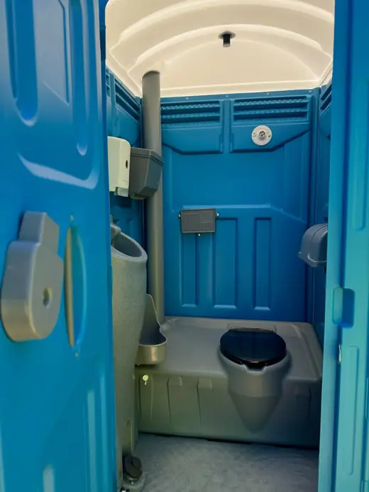 Clean porta potty interior with paper holder and sanitizer dispenser