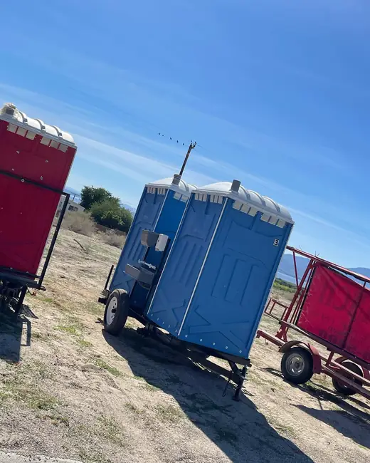 Trailer-mounted porta potties at an open field work site